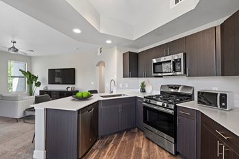 A modern kitchen with dark wood cabinets and stainless steel appliances.